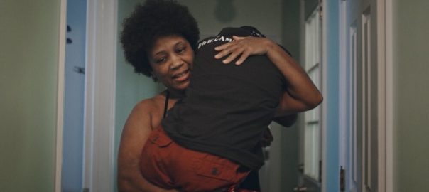 A woman carries someone in her arms, embracing them.