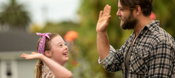 A woman with Down syndrome and a man reach towards each other for a high five.