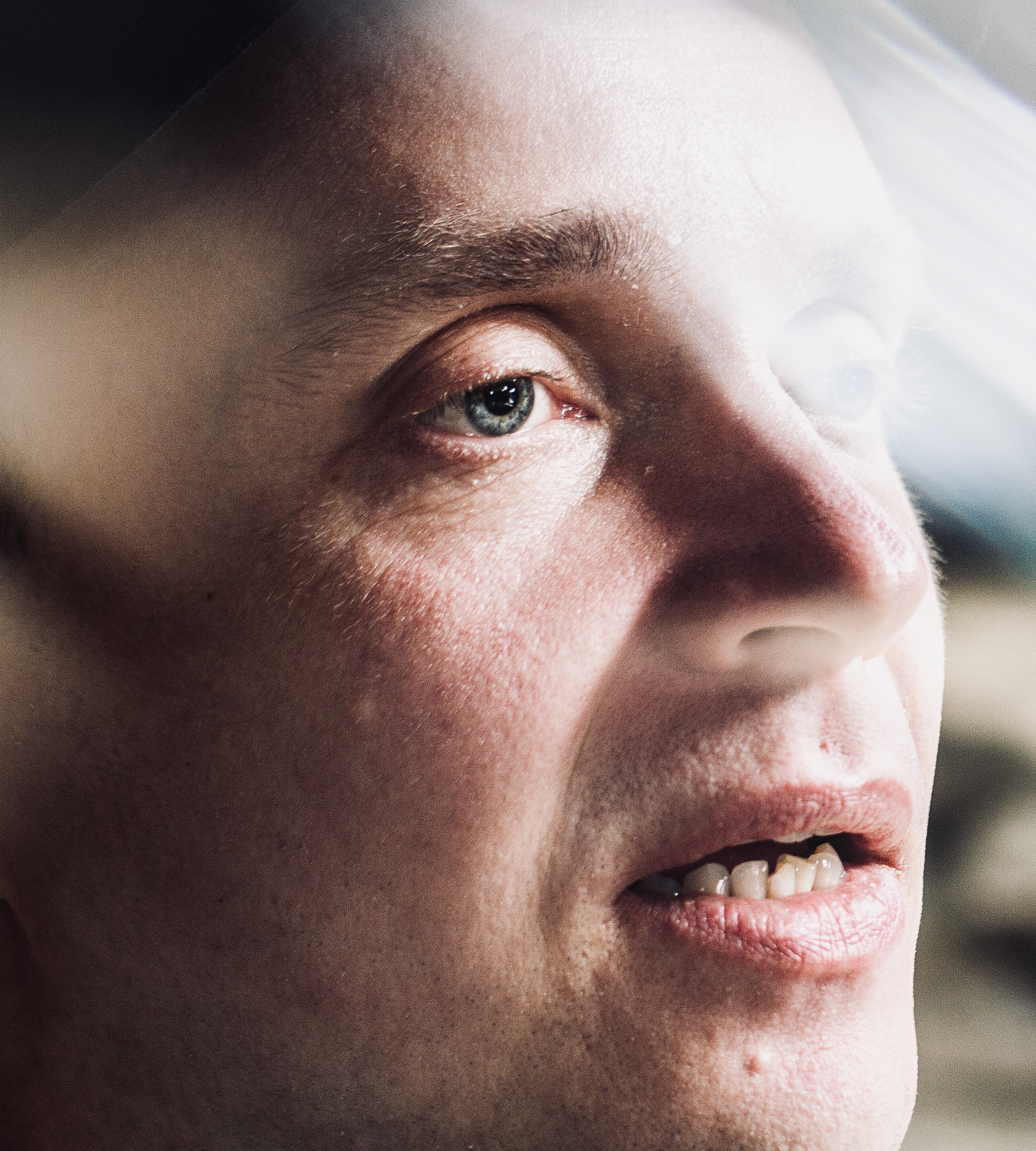 A man gazes out with a vacant expression, surrounded by disorienting bright lights.