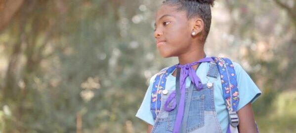 a young black girl wearing a purple cape