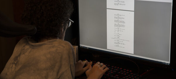 a man leaning towards a computer screen, his hands on the keyboard