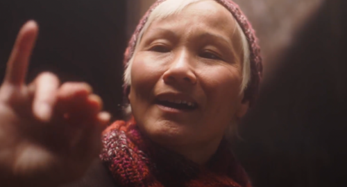 an aged asian woman making a signing gesture