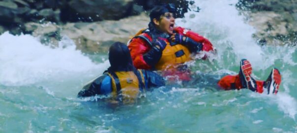 2 people in rafting suits gasping for air in troubled water